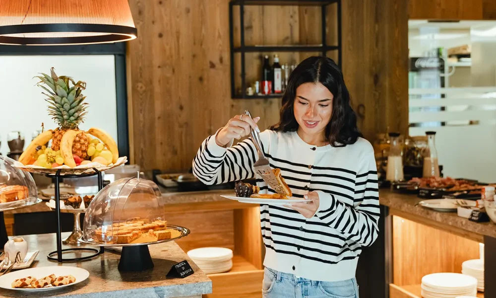 Donna che si serve al buffet di un ristorante con una selezione di dolci e frutta.