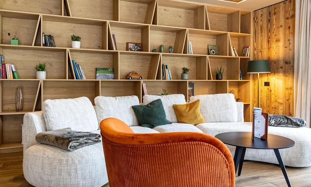 Salotto moderno con mobili in legno, divano bianco e poltrona arancione.