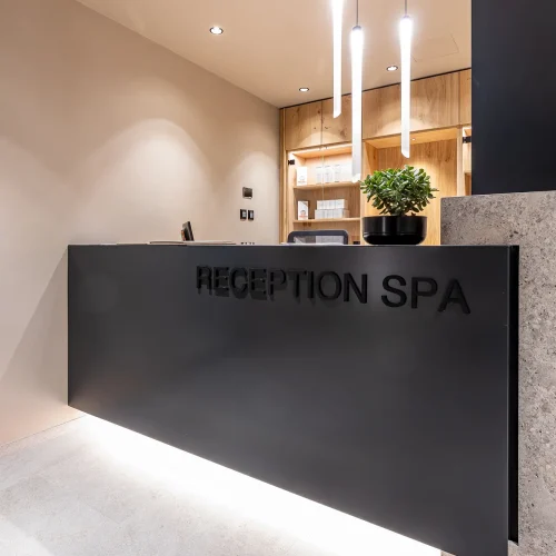 Reception moderna di una spa con arredamento minimalista e illuminazione elegante.