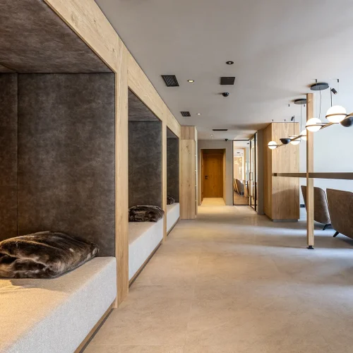 Corridoio moderno con sedute imbottite e illuminazione pendente elegante.