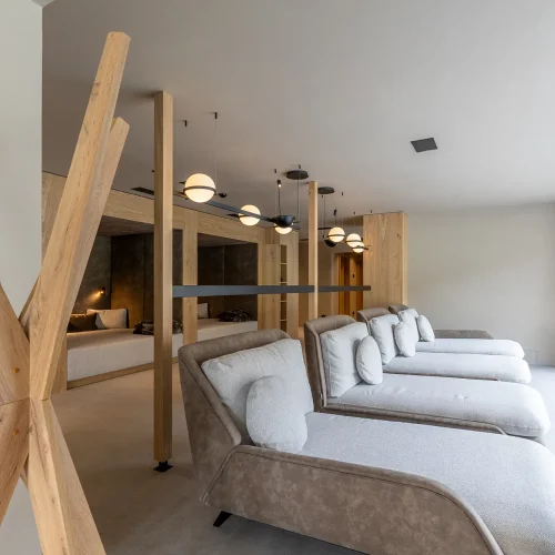 Zona relax moderna con lettini e illuminazione elegante vicino a una grande vetrata.