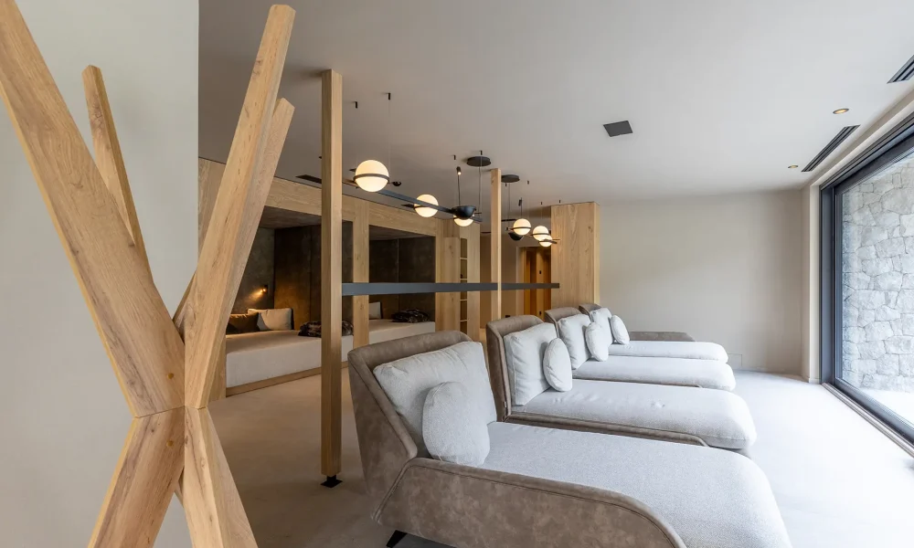 Zona relax moderna con lettini e illuminazione elegante vicino a una grande vetrata.
