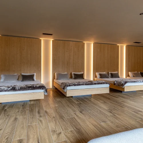 Sala relax con letti moderni in legno e illuminazione soffusa.