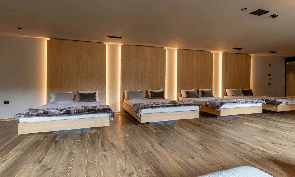Sala relax con letti moderni in legno e illuminazione soffusa.