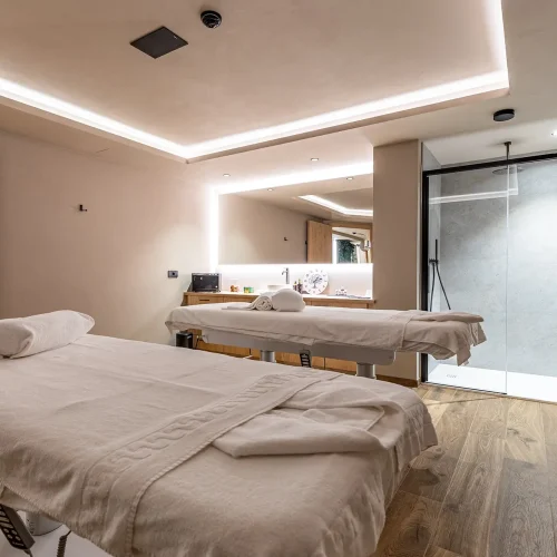 Sala massaggi moderna con due lettini e illuminazione soffusa.