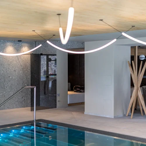Interno di una moderna piscina coperta con illuminazione elegante e arredamento sofisticato.