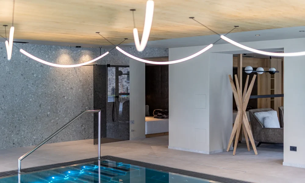 Interno di una moderna piscina coperta con illuminazione elegante e arredamento sofisticato.