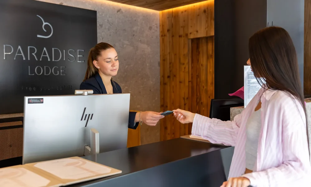 Una donna alla reception di un hotel consegna una chiave a un'ospite.