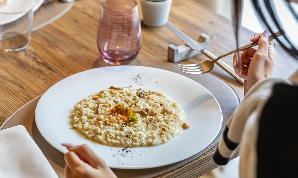 Persona seduta a tavola che mangia un risotto al ristorante.