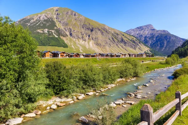 Paesaggio alpino con un fiume che scorre attraverso la valle e montagne sullo sfondo.